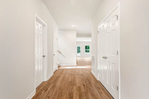 Bright hallway in Somerset Hill with light wood flooring, white walls, and a sunlit room ahead.