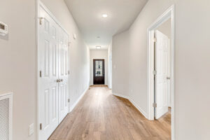 Bright hallway in Somerset Hill with wood floors, white doors, and ceiling lights—Lot 8 features a striking dark end door.