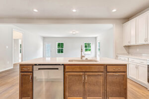Modern kitchen at Somerset Hill Lot 8 features a center island, wood cabinets, and open views of living area and windows.