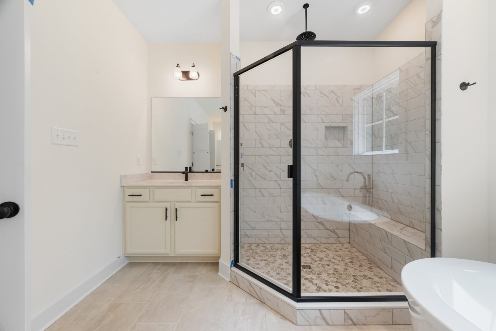 Modern bathroom at Shirley Commons Lot 7 features a glass-enclosed shower, built-in tub, and light tile flooring.