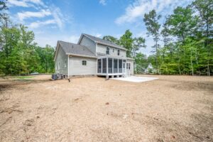 Two-story gray home on Lot 7, Shirley Commons, with screened porch and large dry yard surrounded by trees.