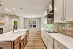 Modern kitchen at Lot 7, Somerset Hill with white cabinets, farmhouse sink, wood floors, and dining area view.