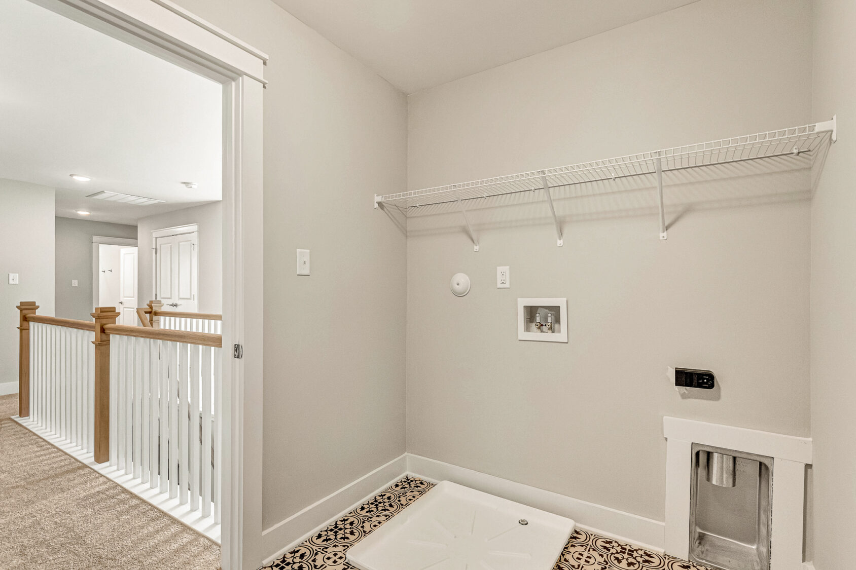 Lot 7 Somerset Hill: Empty laundry room with wire shelf, washer hookup, pet door, patterned tile, and beige walls.
