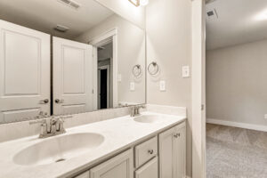 Somerset Hill Lot 7: Double sink vanity, white countertop, mirror, open doors, towel rings, and bright lighting.