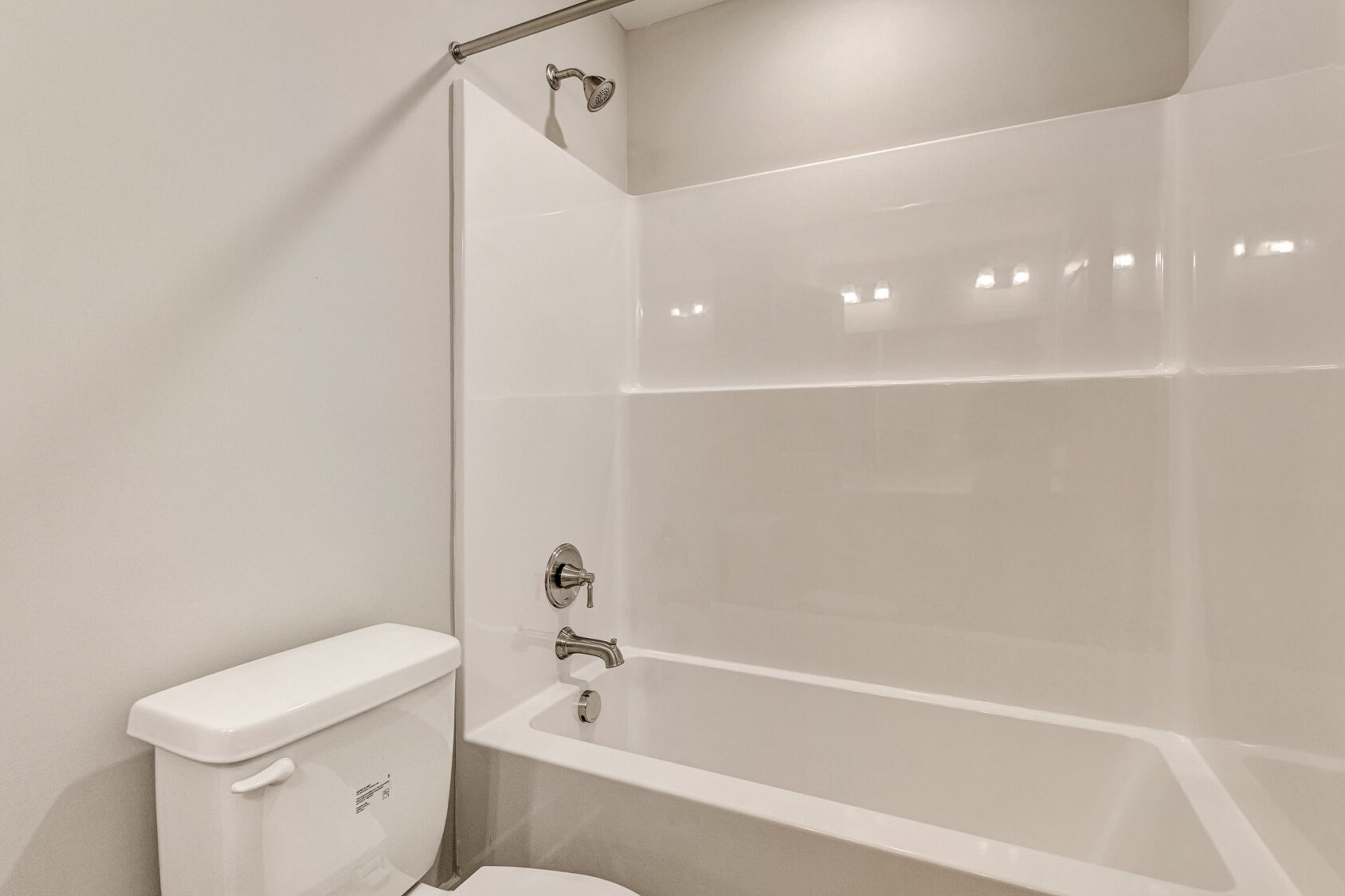 White bathtub and shower combo in Lot 7, Somerset Hill, with chrome fixtures beside a toilet in a neutral bathroom.