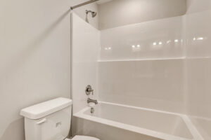 White bathtub and shower combo in Lot 7, Somerset Hill, with chrome fixtures beside a toilet in a neutral bathroom.