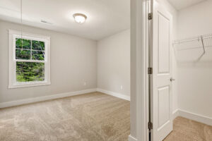 Empty carpeted bedroom in Somerset Hill, Lot 7, with window, ceiling light, and closet with a wire shelf.
