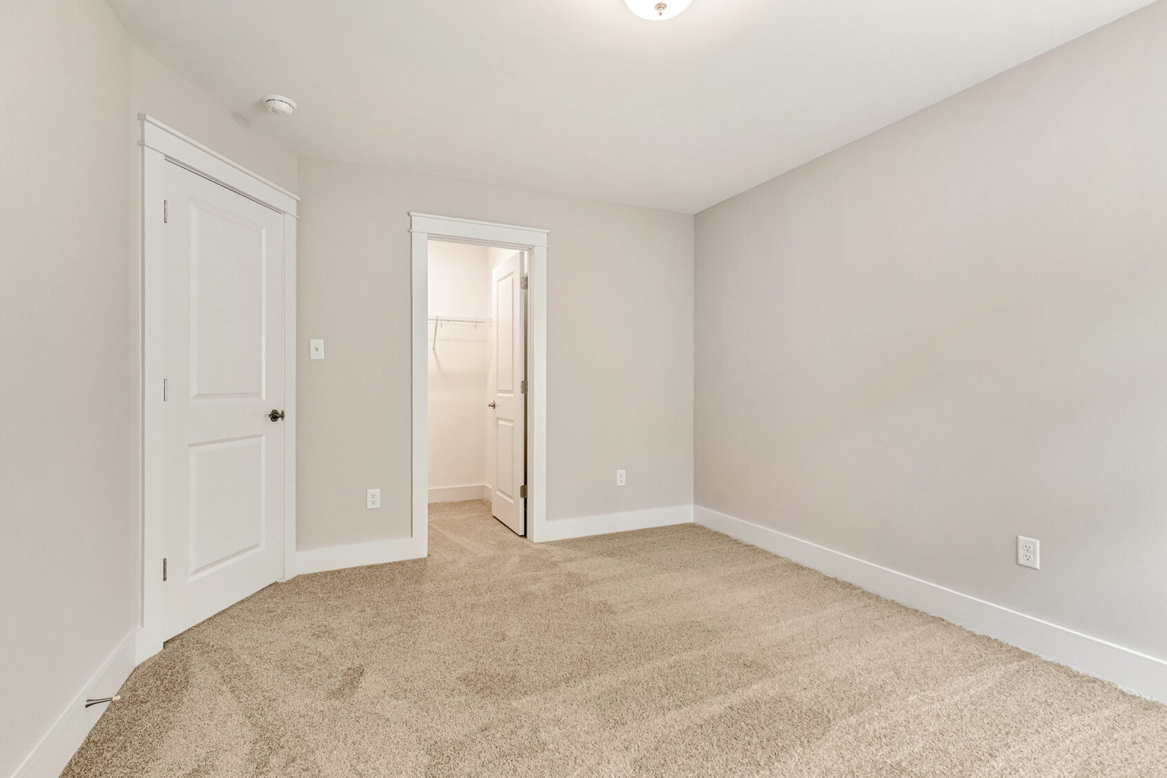 Spacious Somerset Hill Lot 7 room with beige carpet, white trim, two doors, and an open closet with shelving.