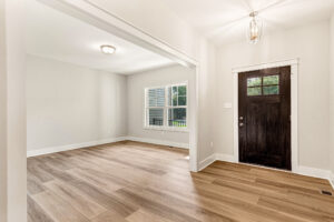 Bright Somerset Hill entryway with wood flooring, white walls, large window, and a dark wooden door with glass panels.