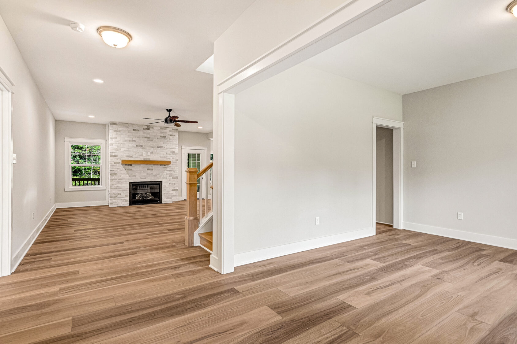 Bright living room in Somerset Hill, Lot 7 with wood floors, fireplace, and large windows filling the space with light.