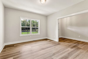 Bright empty room with wood floors in Somerset Hill, a window, neutral walls, and an open doorway to Lot 7.