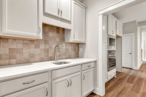 Modern kitchen in Somerset Hill, Lot 7, with white cabinets, tile backsplash, and built-in appliances on wood flooring.