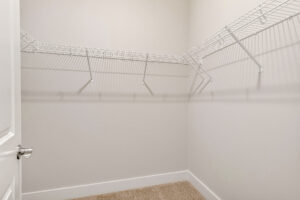 Empty walk-in closet in Lot 7, Somerset Hill; beige carpet, white walls, white wire shelves along two sides.