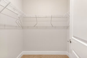 Empty walk-in closet in Lot 7, Somerset Hill; white wire shelves, beige carpet, plain walls, door slightly open right.