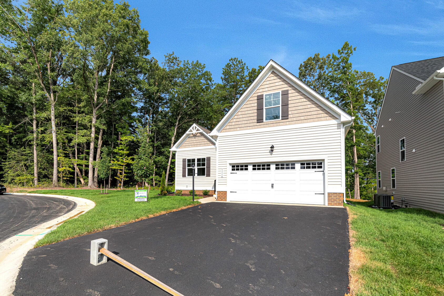Lot 4 at Somerset Hill: New single-family house with two-car garage, driveway, lawn, and trees on a curved street.