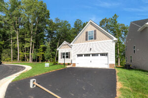 Lot 4 at Somerset Hill: New single-family house with two-car garage, driveway, lawn, and trees on a curved street.