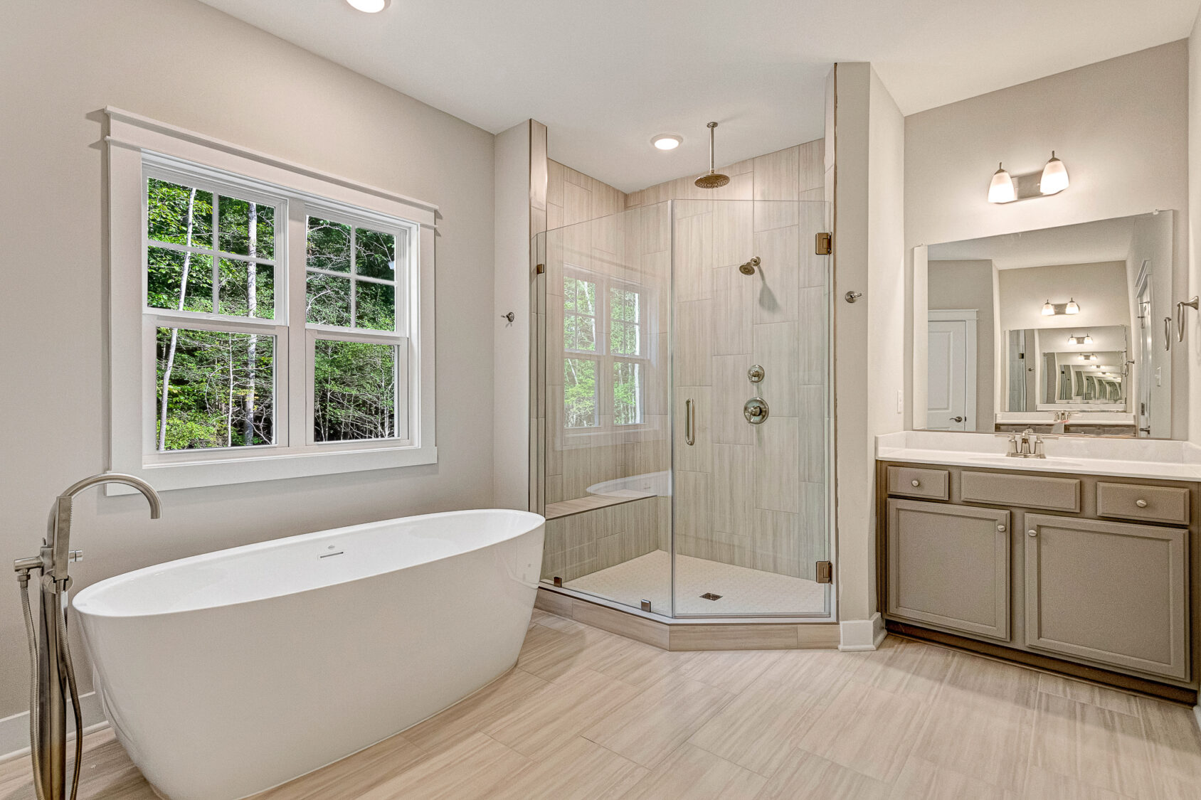 Modern bathroom at Somerset Hill Lot 7 with a freestanding tub, glass shower, double sink vanity, and scenic window views.