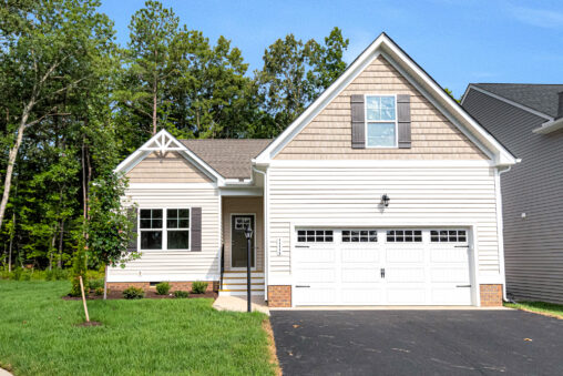Charming single-story beige home on Somerset Hill Lot 4, with a two-car garage, green lawn, and trees behind.