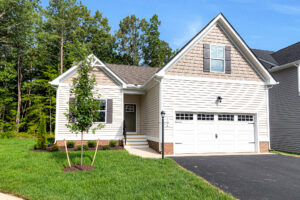 Lot 4, Somerset Hill: Light-colored suburban house with two-car garage, green lawn, and young trees on a sunny day.