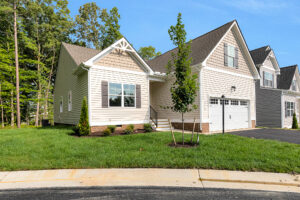 Charming single-story beige home on Somerset Hill, Lot 4, featuring black shutters and a lush yard with young trees.