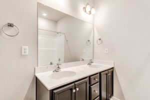 Somerset Hill Lot 4: Double-sink vanity with dark cabinets, large mirror, and bright overhead lighting.