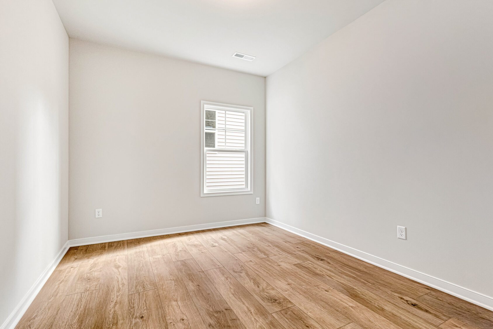 Empty room in Somerset Hill's Lot 4, with light wood flooring, white walls, and a single sunlit window.