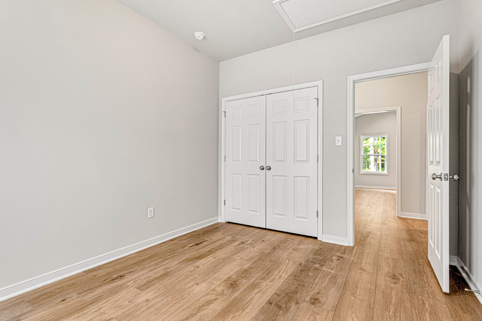 Empty room in Somerset Hill with wood floor, double closets, open door, and window; part of Lot 4.