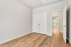Empty room in Somerset Hill with wood floor, double closets, open door, and window; part of Lot 4.