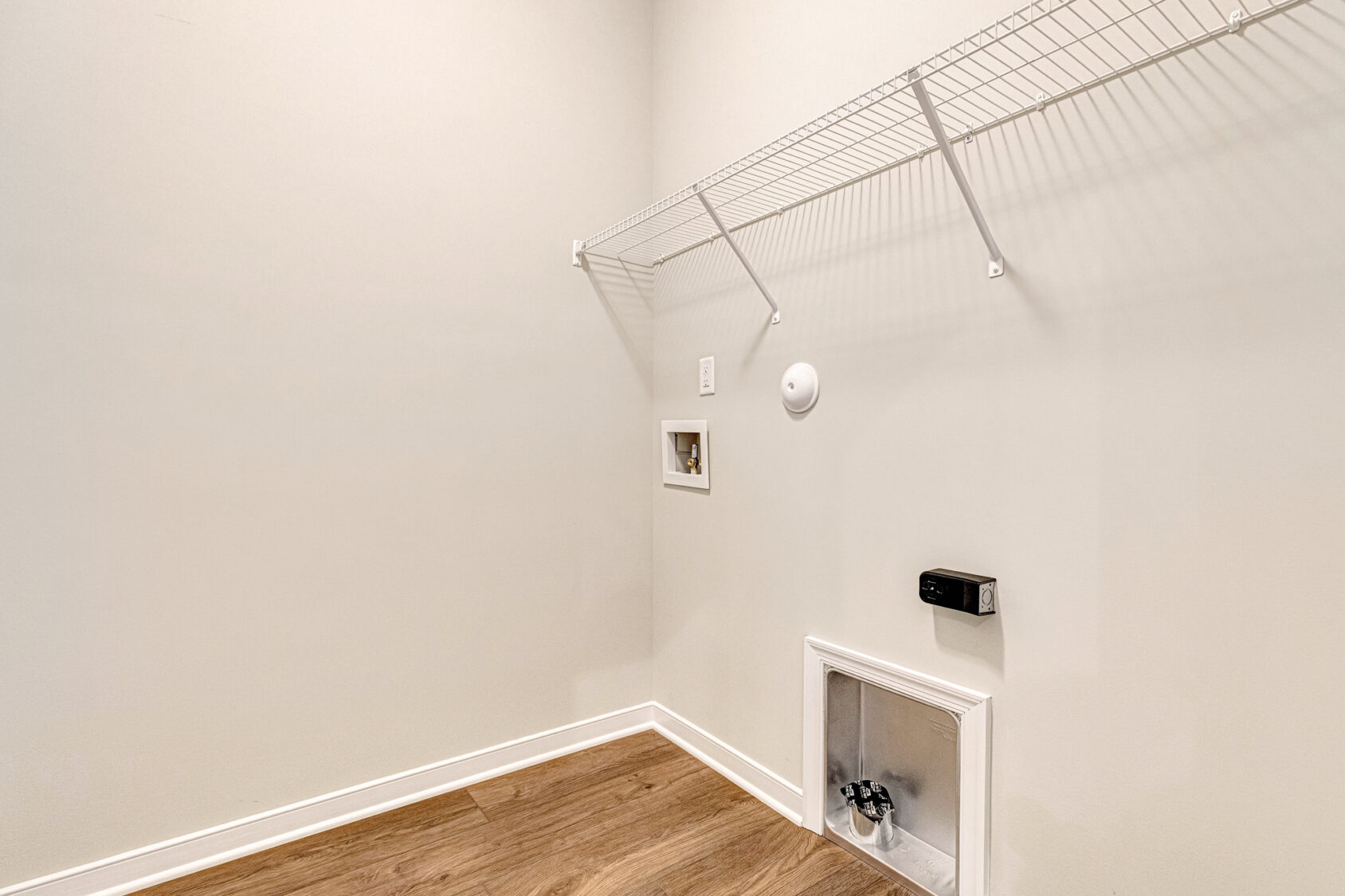 Somerset Hill Lot 4: Empty laundry room with wire shelf, washer/dryer hookups, and light wood flooring.