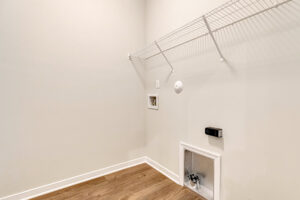Somerset Hill Lot 4: Empty laundry room with wire shelf, washer/dryer hookups, and light wood flooring.