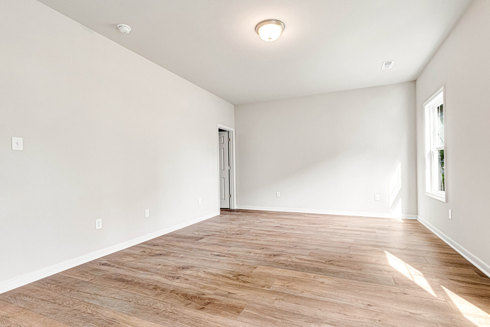 Empty room at Somerset Hill with white walls, wooden floor, and sunlight through two windows on the right. Lot 4.