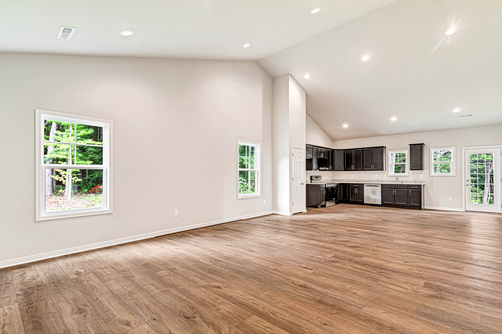Spacious open-concept room in Somerset Hill, featuring wood floors, white walls, and a modern kitchen with dark cabinets.