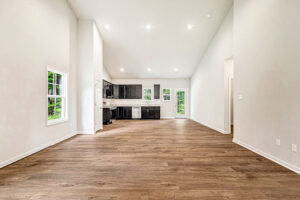 Spacious open-concept living area at Lot 4, Somerset Hill, with wood floors and a modern kitchen featuring black cabinets.