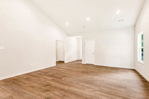 Bright empty room with wood floors, white walls, recessed lights, and multiple doors in Somerset Hill Lot 4.