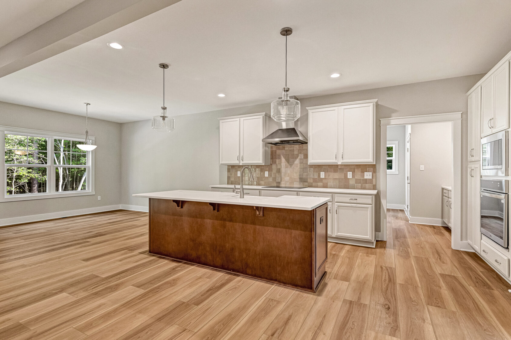 Modern Somerset Hill kitchen with wood floors, white cabinets, an island, pendant lights, and a scenic Lot 7 window view.