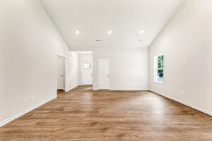Empty room in Somerset Hill's Lot 4 with wood flooring, white walls, recessed lights, a window, and three white doors.