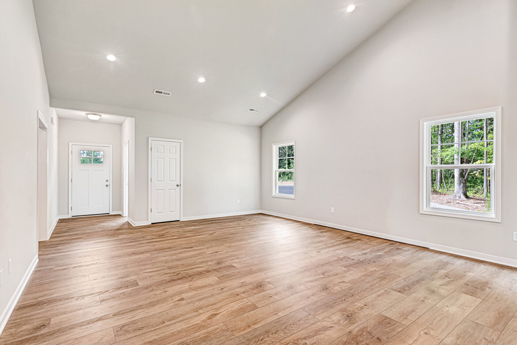 Empty room in Somerset Hill, Lot 4 with wood floors, vaulted ceiling, recessed lights, and scenic windows.