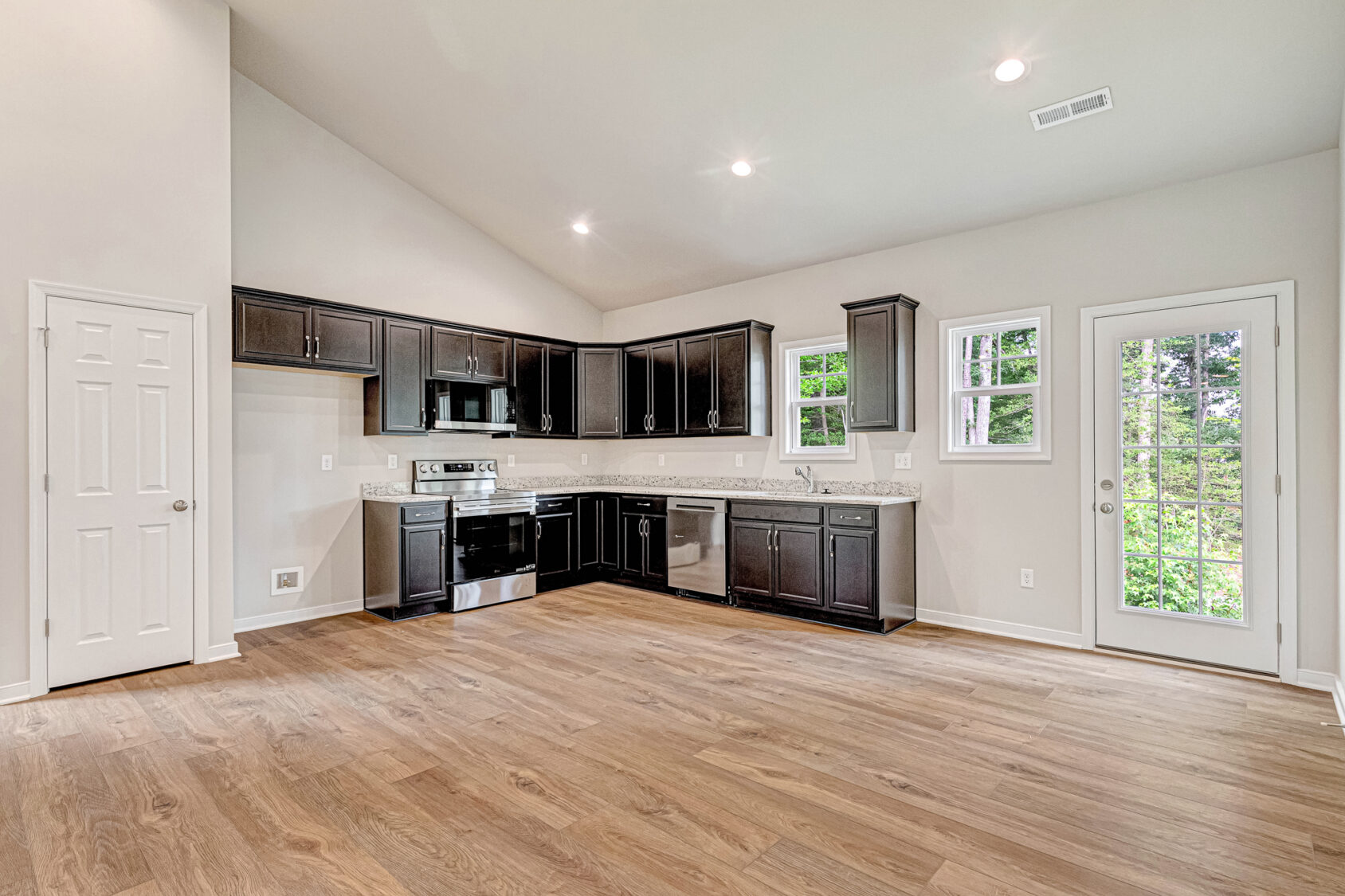 Modern kitchen in Somerset Hill's Lot 4 with dark cabinets, wood floors, and stainless steel appliances.