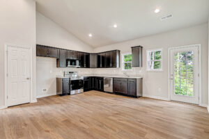 Modern kitchen in Somerset Hill's Lot 4 with dark cabinets, wood floors, and stainless steel appliances.