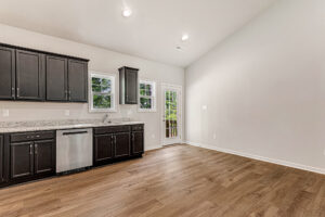Modern Somerset Hill kitchen with dark cabinets, stainless appliances, wood floors, and a door to Lot 4’s yard.