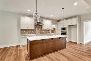 Modern Somerset Hill kitchen with white cabinets, large island, wood floors, and stainless steel appliances. Lot 7.