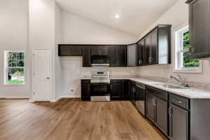 Modern kitchen in Somerset Hill with dark cabinets, stainless steel appliances, granite tops, and wood flooring.