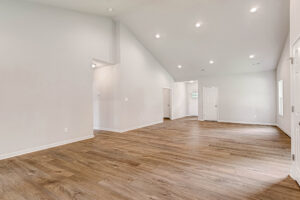 Spacious, empty room in Somerset Hill’s Lot 4 with wood flooring, white walls, recessed lights, and a vaulted ceiling.