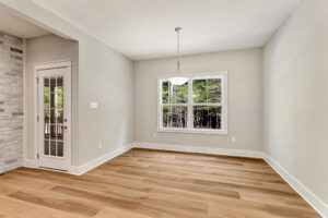 Empty room at Somerset Hill, Lot 7 features light wood floors, white walls, a window, and door to the outside.