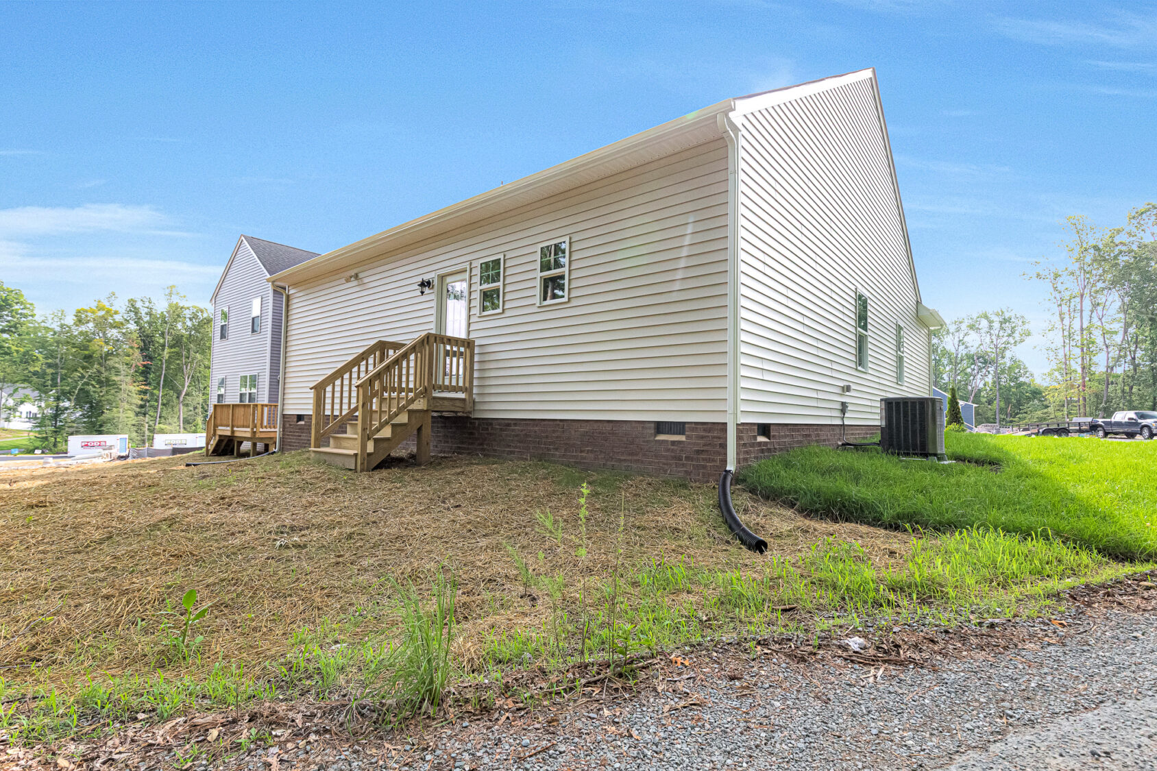 Lot 4, Somerset Hill: White single-story house with small wooden porch, brick foundation, and grassy yard under a blue sky.