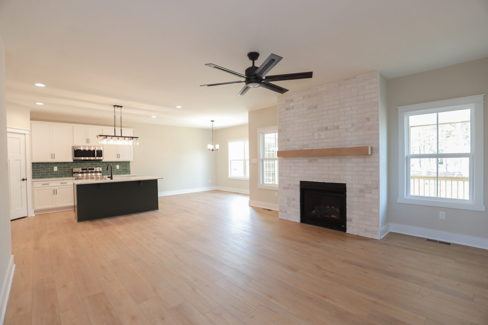 Spacious open-plan living area with kitchen, fireplace, and large windows in Lot 6 at Somerset Hill. Light wood flooring.
