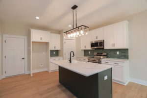 Modern Somerset Hill kitchen with white cabinets, green tile backsplash, island, and stainless appliances under pendants.