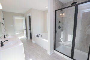 Modern Somerset Hill bathroom with double sinks, a bathtub, and glass shower. Light gray tiles throughout Lot 6.