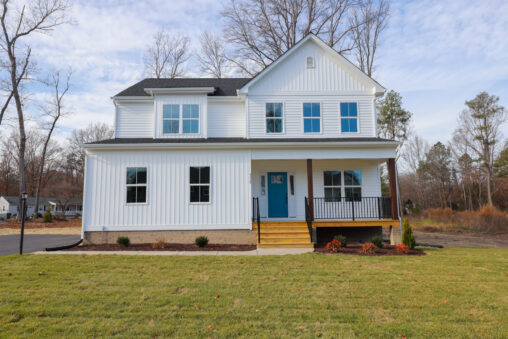 Two-story white house on Lot 6, Somerset Hill, with a blue door, covered porch, and large grassy yard on a clear day.