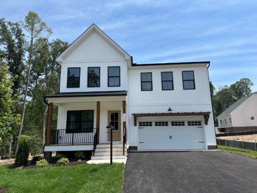 Modern two-story white house with black trim on Somerset Hill, Lot 20, features a porch and double garage under blue skies.